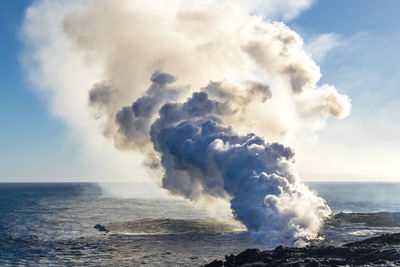 Eruption of a volcano on hawaiian island on ocean. volcanic activity. field of frozen black lava