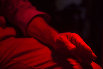 Close-up midsection of man with red light in dark