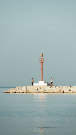 Lighthouse by sea against clear sky