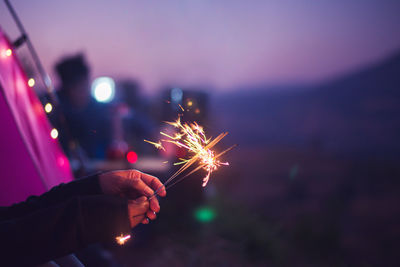 Cropped hand of person holding illuminated sparklers