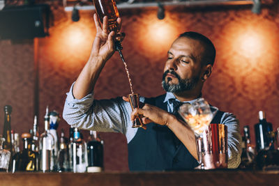 Mature bartender preparing cocktail on bar counter