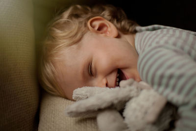 Close-up of cute baby boy laughing on sofa at home