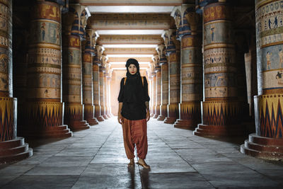 Full length portrait of woman wearing scarf standing by architectural columns