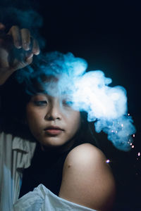 Young woman holding illuminated sparkler at night