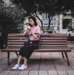 Full length of woman sitting on bench in park