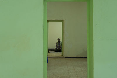 Portrait of man standing against door of building