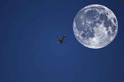 Low angle view of airplane against moon in sky