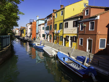 Boats moored in canal amidst buildings against sky