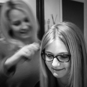 Mother brushing daughter hair at home