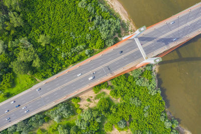 City car moving at highway bridge on background smooth river surface drone view. aerial view