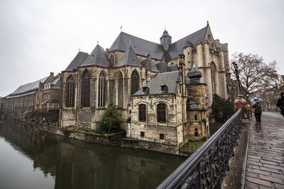 View of old building by canal against sky