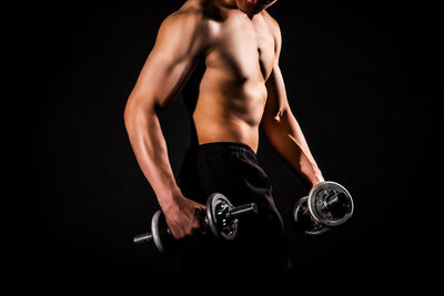 Midsection of shirtless man against black background