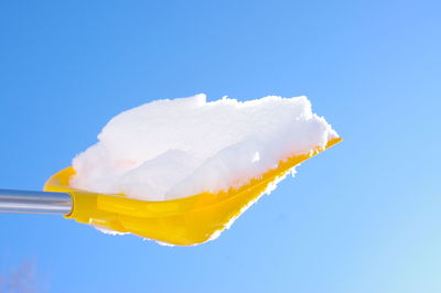 Low angle view of snow on shovel against clear sky