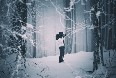 Woman standing on snow covered forest