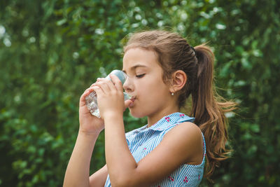 Side view of girl drinking water from glass