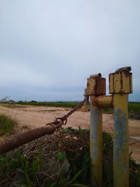 Old wooden post on field against sky