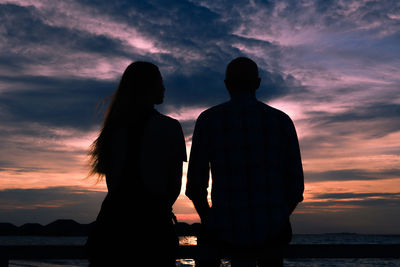 Silhouette people standing against sea during sunset