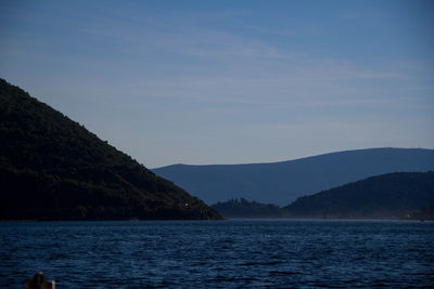 Scenic view of sea by mountains against sky