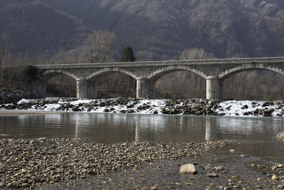 Arch bridge over river against trees