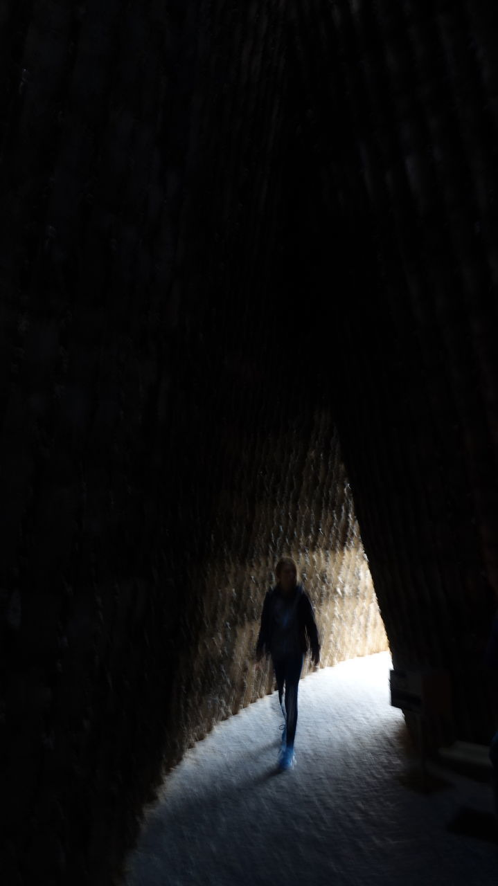 REAR VIEW OF SILHOUETTE PERSON WALKING IN TUNNEL AT NIGHT