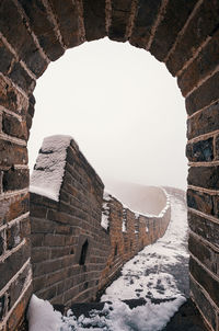 Arch leading towards walkway with snow against clear sky during winter