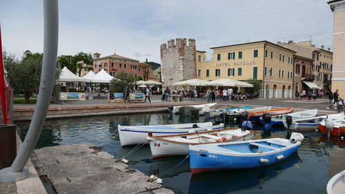 Boats moored in canal amidst buildings in city against sky