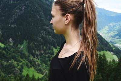 Side view of beautiful woman standing against mountain