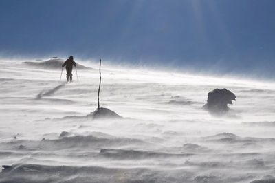 Person skiing on snow field against clear sky