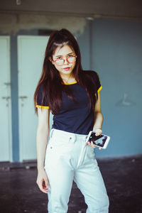 Portrait of young woman standing against wall