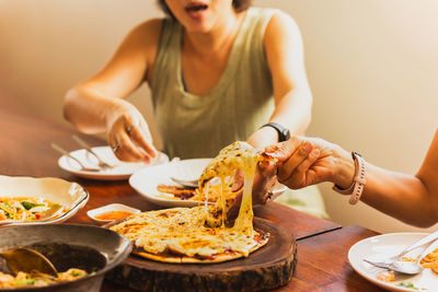Woman hands taking slices of pizza with friends.