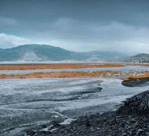 Scenic view of lake against mountains and cloudy sky