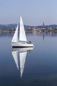 Sailboat sailing on lake against clear sky