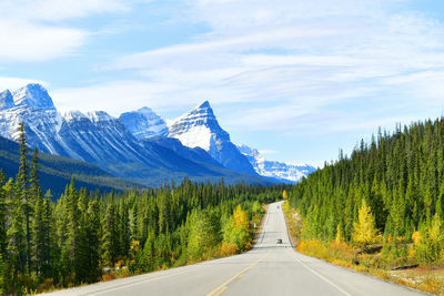 Road leading towards mountains against sky