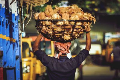 Man carrying coconuts in basket for sale