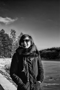 Portrait of cheerful woman wearing warm clothing at lakeshore