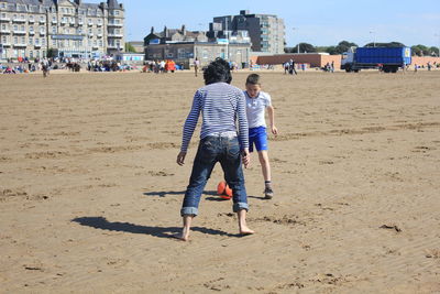 Rear view of people walking on sand