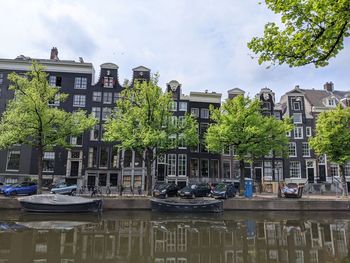 Boats in canal by buildings in city against sky
