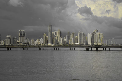 Sea by modern buildings against sky in city