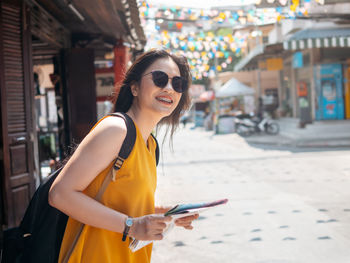 Side view of woman holding map while standing outdoors