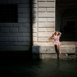 Full length of woman standing against brick wall