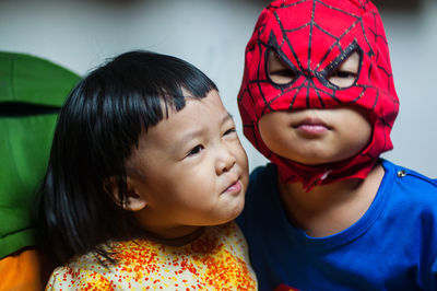 Close-up of boy in superman costume with sister at home