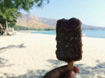 Close-up of hand holding ice cream cone at beach