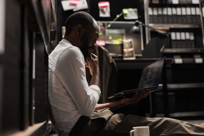 Side view of young woman using laptop while sitting in cafe