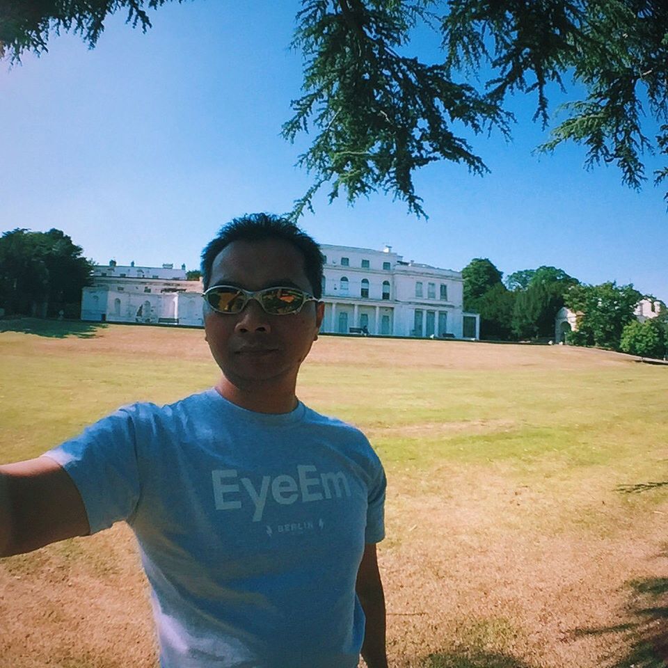 lifestyles, person, leisure activity, casual clothing, portrait, clear sky, looking at camera, smiling, tree, standing, young adult, architecture, built structure, building exterior, front view, young men, happiness, blue