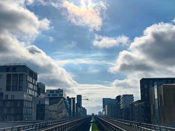 Railroad tracks amidst buildings in city against sky
