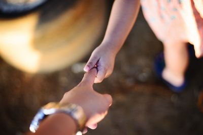 Cropped image of mother and daughter with holding hands outdoors