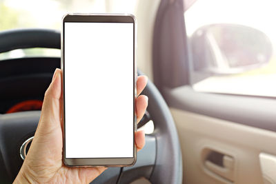 Cropped hand of woman holding mobile phone in car