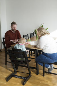 Side view of woman sitting on chair at home