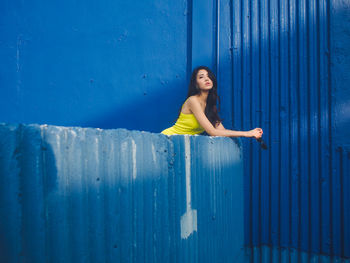 Portrait of smiling girl standing against blue wall