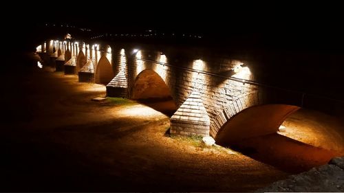 Illuminated bridge over river at night